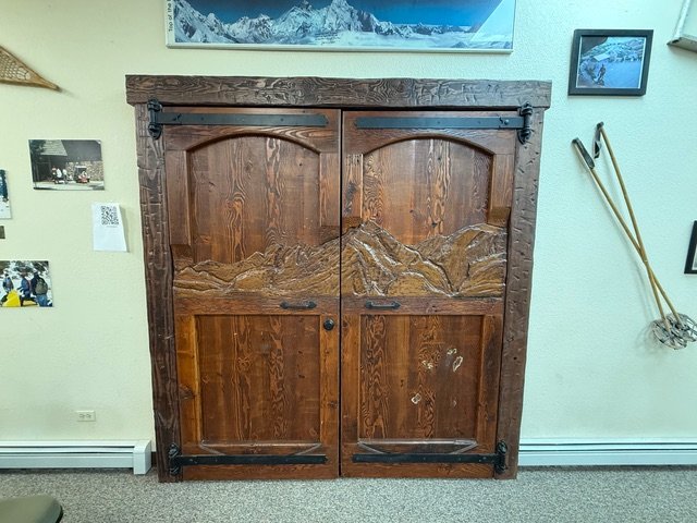 Hand-carved wooden double doors with a mountain range relief