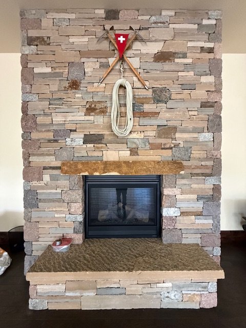 Stone fireplace with crossed ice axes, a Swiss flag and a coiled climbing rope